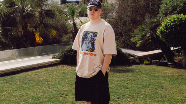 Lyttä seisoo trooppisessa puutarhassa, päällään kuvitettu t-paita, edustamassa Def Jam Recordings Finland -levy-yhtiötä.