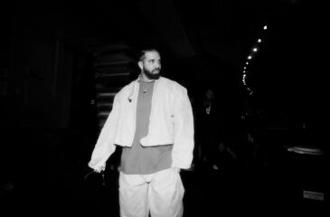 Drake kävelee lavan takana tummassa taustassa