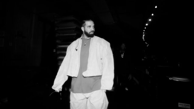 Drake kävelee lavan takana tummassa taustassa