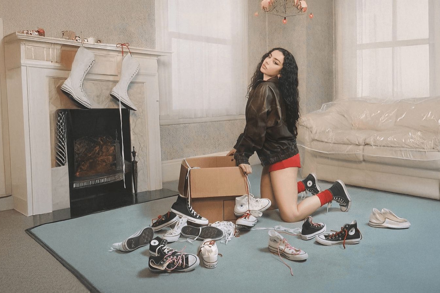 Charli XCX Converse-kenkäkasan vieressä. Charli XCX ja Converse yhdistävät voimansa.